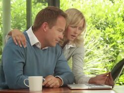 Medium shot of male and female at dinning table looking at computer Stock Footage