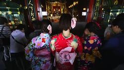 Camera captures young Japanese women wearing Furisode (Japanese Long-sleeved kimono), who are throw a coin into the Saisenbako (Offering Box) and clap their hands twice and pray at Gokuden (Kannon Hall) at inside of Sensoji Temple Main Hall (Asakusa Kanno Stock Footage