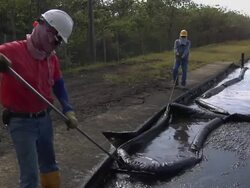 WS Two workers cleaning up and raking oil sludge / Bogota, Colombia Stock Footage