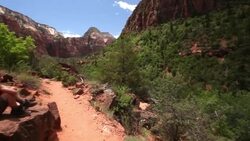 Pan from rocky mountains to young boy sitting on rock resting from his hike and admiring the view in Zion National Park Stock Footage