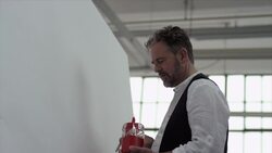 Artist starts painting with red color on canvas Stock Footage