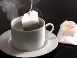  MS Tea bag being dropped into teacup filled with hot water / Los Angeles, California, United States Stock Footage
