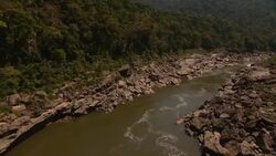 A narrow river flows past boulders and a forest. Stock Footage