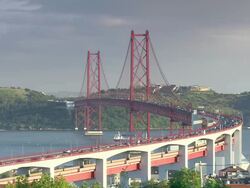 WS View of traffic at"Ponte 25 de Abril" while cargo ship is crossing Tagus River and "Cristo Rei" / Lisbon, Portugal   Stock Footage