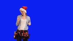 slender young woman construction worker in a cap of Santa Claus on a blue background Stock Footage