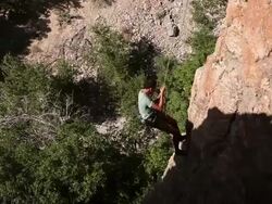 Handheld blurred shot of a rock-climber descending a cliff. Stock Footage
