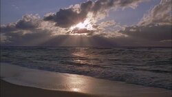 A golden hour sky reflects in ocean waves washing up on beach in Sylt. Stock Footage