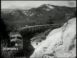 1947: DIESEL TRAINS: HA EXT WS Santa Fe trains in yard, Barstow, California. VS Diesel train passing, taking turn on railroad tracks on mountainous bend, train on mountain side. INT VS Passengers in astro-dome car. (POV top of train) CU Train turning. Instructional Video