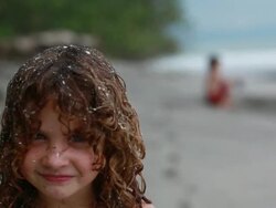 MS R/F Little girl walks to into  covered in sand and sticks tongue out with man and boy on beach / Montezuma, Puntarenas, Costa Rica Stock Footage