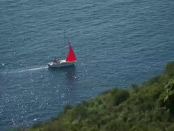 MS View of Boat with red sail in tuscan archipelago in argentario mountain / Grosseto, Tuscany, Italia Stock Footage