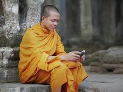 MS A Buddhist monk taps on the screen of a smartphone on the steps of an ancient temple in Angkor Wat / Siem Reap, Cambodia Stock Footage