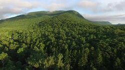 4K aerial shot climbing slowly up the side of a mountain surrounded by clouds Stock Footage