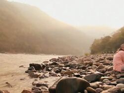 Two senior couple drinking coconut water at riverbank, Ganges River, Rishikesh, Uttarakhand, India Stock Footage