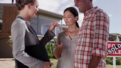 Realtor giving happy couple keys in front of house Stock Footage