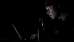 Profile view of surprised man looking at the computer monitor in the dark Stock Footage