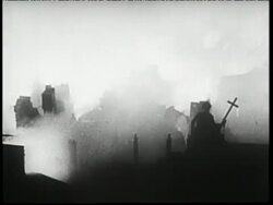 A soldier holds a cross as buildings burn behind him. News Clip