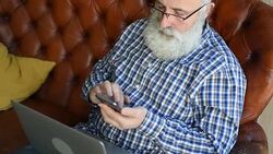 elderly professor is typing a message on a smartphone Stock Footage