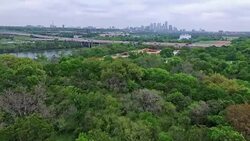 Zilker Park Clubhouse View Austin Texas Greenbelt area next to Colorado River Town Lake and Mopac Extrpessway with boats driving on a cool misty cloudy morning Stock Footage