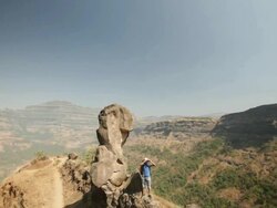 Young man standing on a cliff of mountain and looking through a binocular  Stock Footage