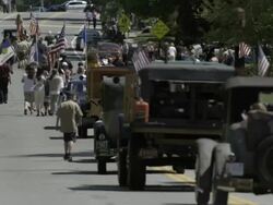 Parade in small town with long row of antique cas, flags, boy scounts, military, marching band, and crowds. Smalltown Americana. Stock Footage