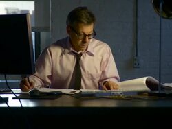 Medium shot. Dolly to the right around man working late at his desk. He sighs as he reads paperwork. Stock Footage
