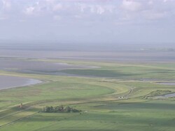 AERIAL PAN View of island surrounded by ocean / Emden + Pilsum, Lower Saxony, Germany Stock Footage