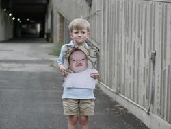 Slow motion of young boy holding up baby photo of himself with cleft palate. Stock Footage