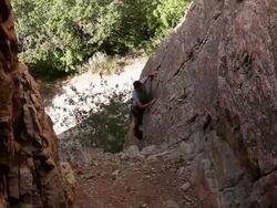 Handheld tilting shot of a man climbing a rock wall. Stock Footage
