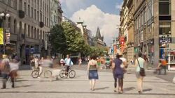 Pedestrians walk past historic buildings in Prague's city center. Stock Footage