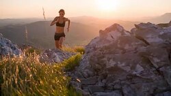Young female athlete running up the mountain at sunset Stock Footage