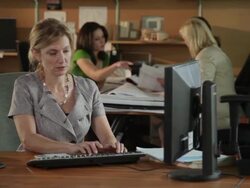 MS PAN Female office worker using computer and getting phone call, colleagues in background / Portland, Oregon, USA Stock Footage