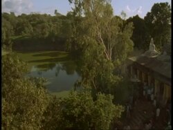WA Lake and trees in jungle, pan right to Hindu temple, Bandhavgarh National Park, India Stock Footage