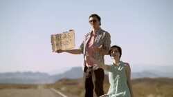 Young hitchhikers thumb a ride from a passing minivan on a lonely desert road, run to catch up Stock Footage