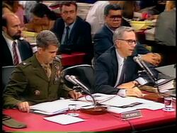 July, 1987 lawyer sitting next to Oliver North talking into microphone during Iran-Contra hearings Stock Footage