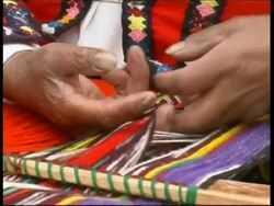 Hands of Inca woman in traditional clothing weaving colourful materials, Peru Stock Footage