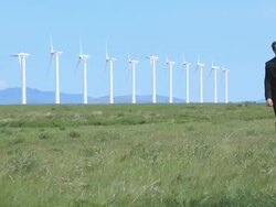 Business man walks with wind turbines Stock Footage