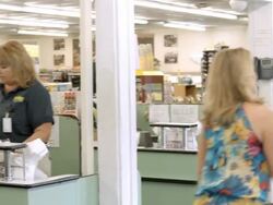 WS PAN from young couple entering grocery store and grabbing shopping cart to young woman at check-out and cashier scanning and bagging groceries / Cabazon, California, USA Stock Footage