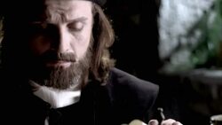 Nostradamus unrolls a parchment and reads it on a cluttered table. Stock Footage