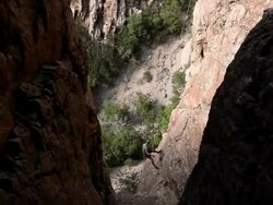 Handheld shot of a rock-climber slowly descending a craggy cliff. Stock Footage