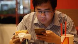 man using smartphone while eating hamburger Stock Footage