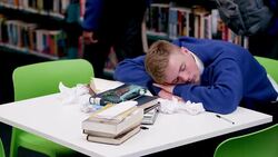Boy sleeping at table in school library Stock Footage