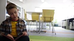 Schoolboy reading book on library floor Stock Footage