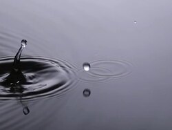 CU SLO MO Drop of Water falling into Water against Grey background / Vieux Pont, Normandy, France Stock Footage
