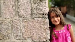 Cute young hispanic girl smiles at camera on third-world street corner (dolly-shot) Stock Footage