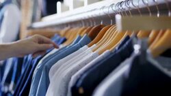 Customer browses rack and picks out shirt at modern clothing store Stock Footage