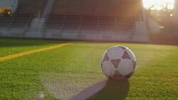 Close-up of soccer ball on stadium field; soccer players kicks ball out of frame Stock Footage