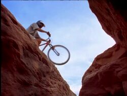 slow motion low angle mountain biker riding over rocks above camera Stock Footage