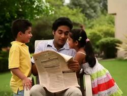 Man reading newspaper with his children playing with him  Stock Footage
