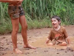 MS Shot of muddy little boy in mud puddle throws mud packs at little muddy girl / Montezuma, Punteranes, Costa Rica Stock Footage