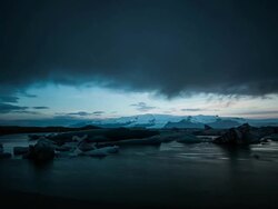 Timelapse at Jokulsarlon Bay with icebergs floating and clouds covering the sky as the camera pans right. Stock Footage